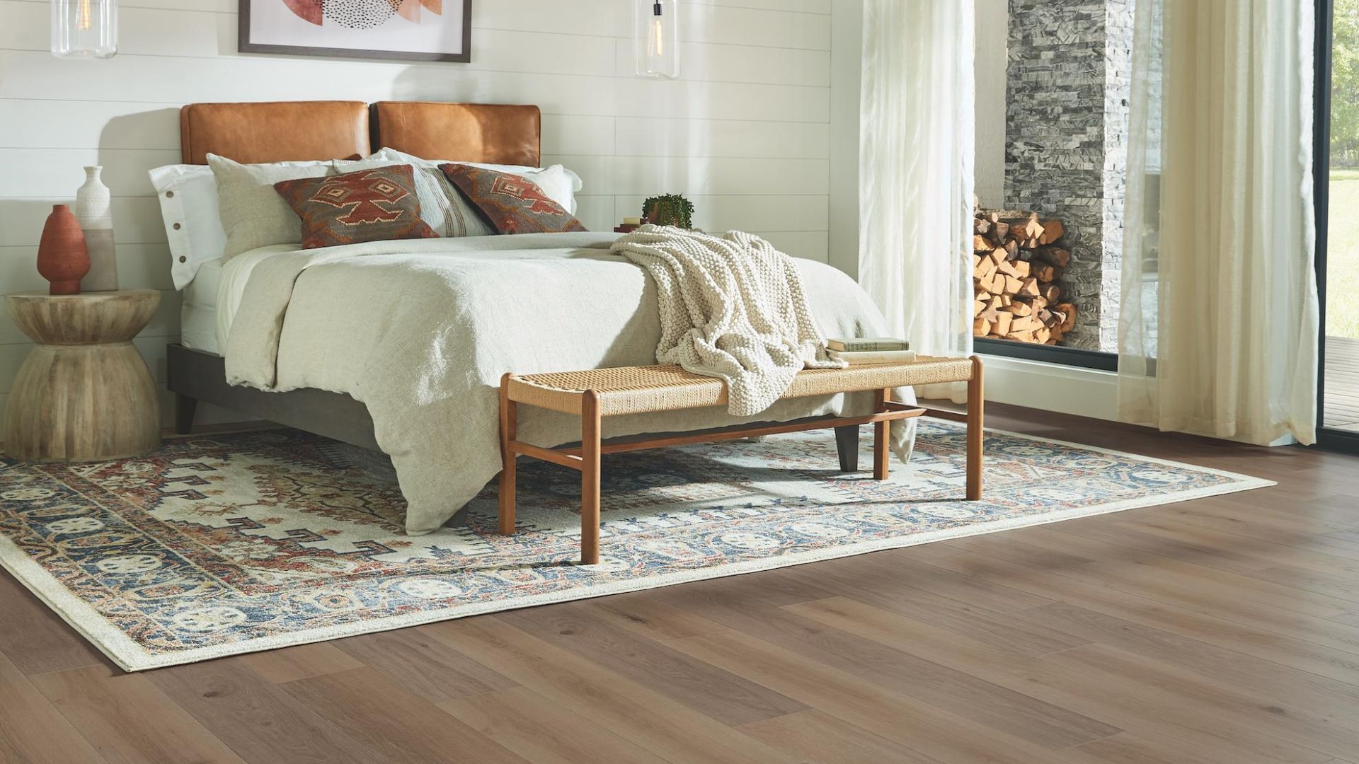 patterned area rug underneath a bed in a large bedroom with wood look laminate flooring